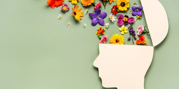 Paper human head symbol and flowers on blue background