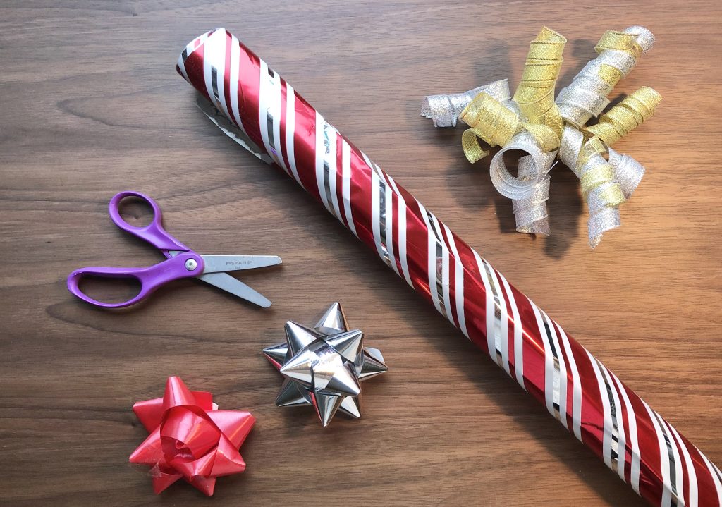 scissors, bows and wrapping paper are scattered across a wooden table