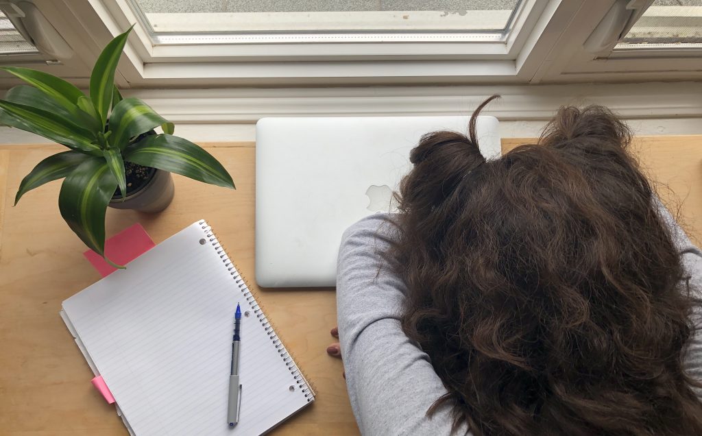 girl with her head down on her desk next to her laptop 