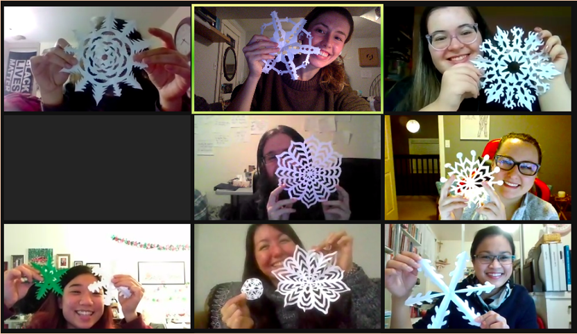 zoom screenshot of smiling Grad Students holding up paper snowflakes