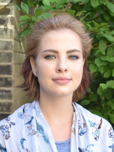 Headshot of smiling young woman with light brown hair in blue and white blouse
