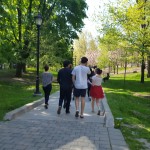 Five people walking down a pathway in a park on a sunny day