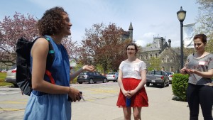 Two students listening to third student speak outside on a sunny day