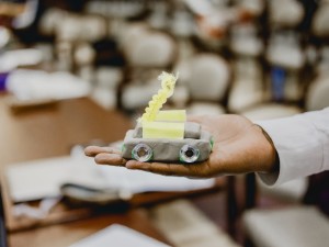 Small car made out of modelling clay in the palm of someone's hand