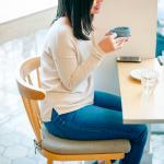 Woman sitting on chair at table drinking coffee