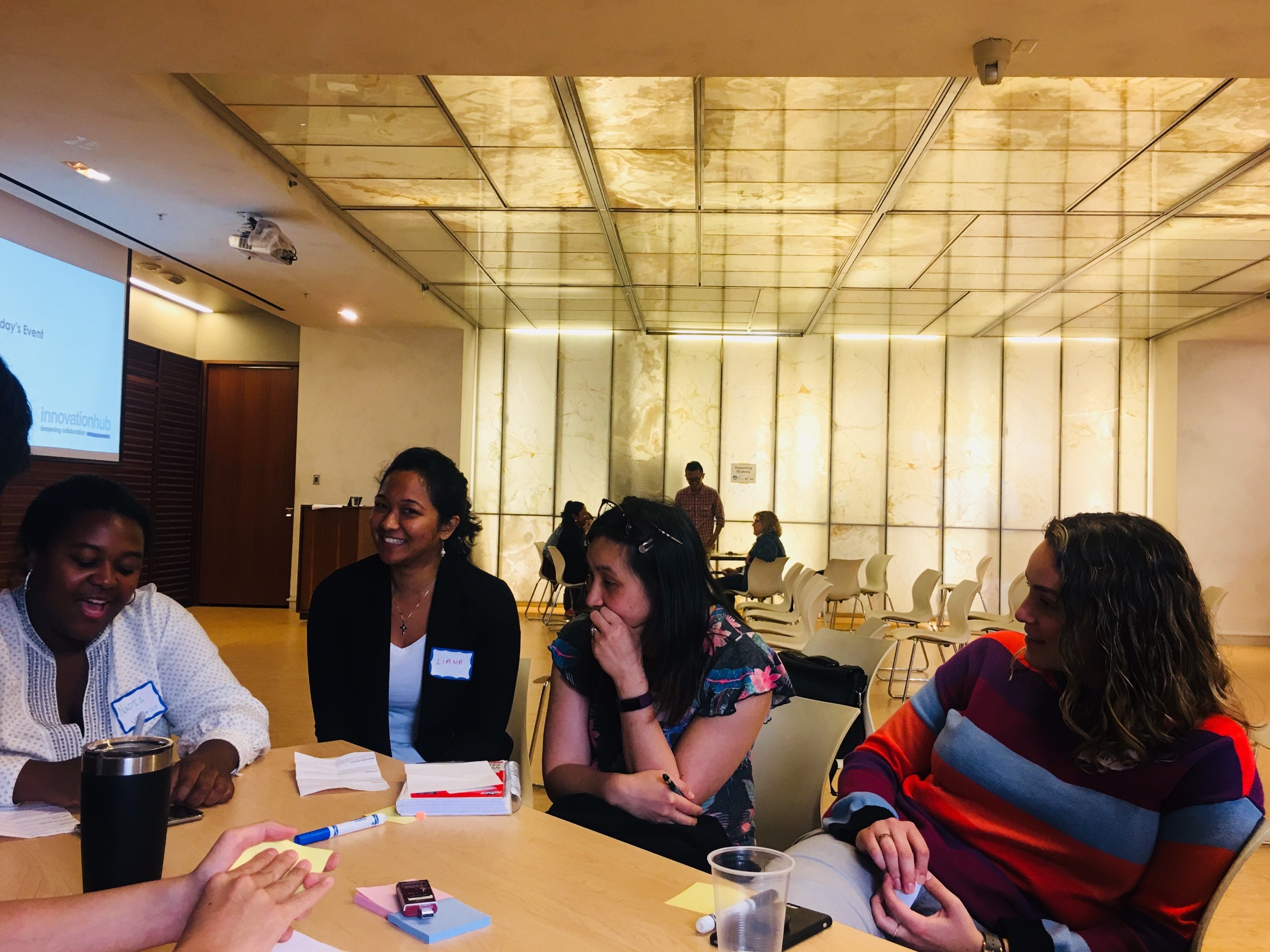 Image from the SLP event, where individuals are sitting at the table chatting and connecting