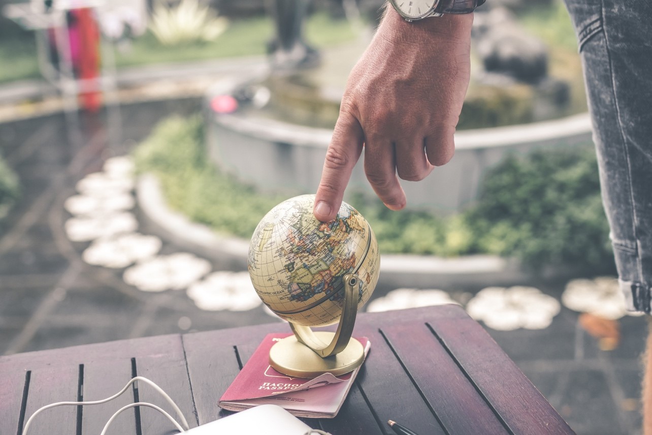 Person pointing at a small globe