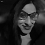 A black and white photo of Nadhiena, smiling to the camera and wearing glasses