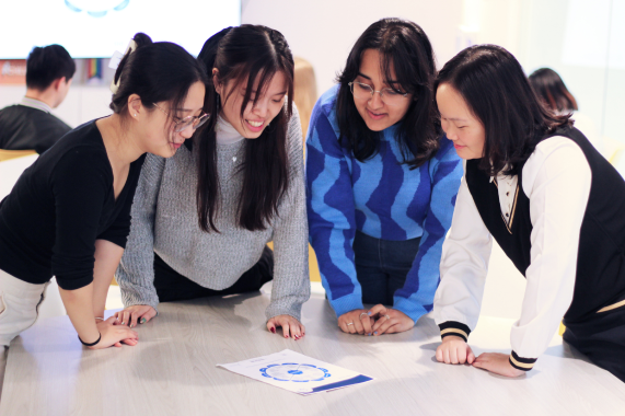 Image of students huddling over a piece of ideating paper, coworking at Innovation Hub