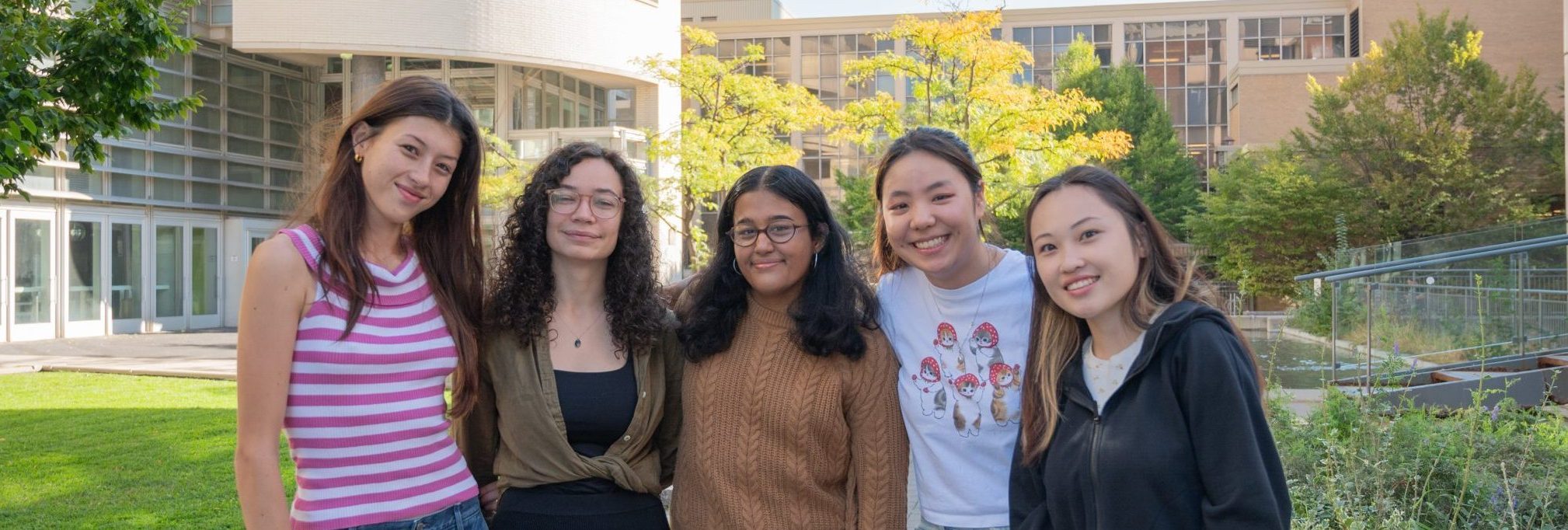 A photo of the Engagement & Belonging - Students with Disabilities team, showing five students standing outdoors, smiling in front of a university building.