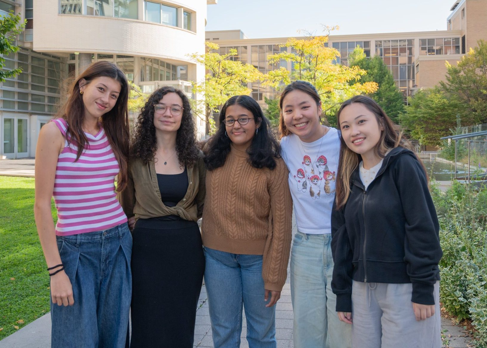 A photo of the Engagement & Belonging - Students with Disabilities team, showing five students standing outdoors, smiling in front of a university building.