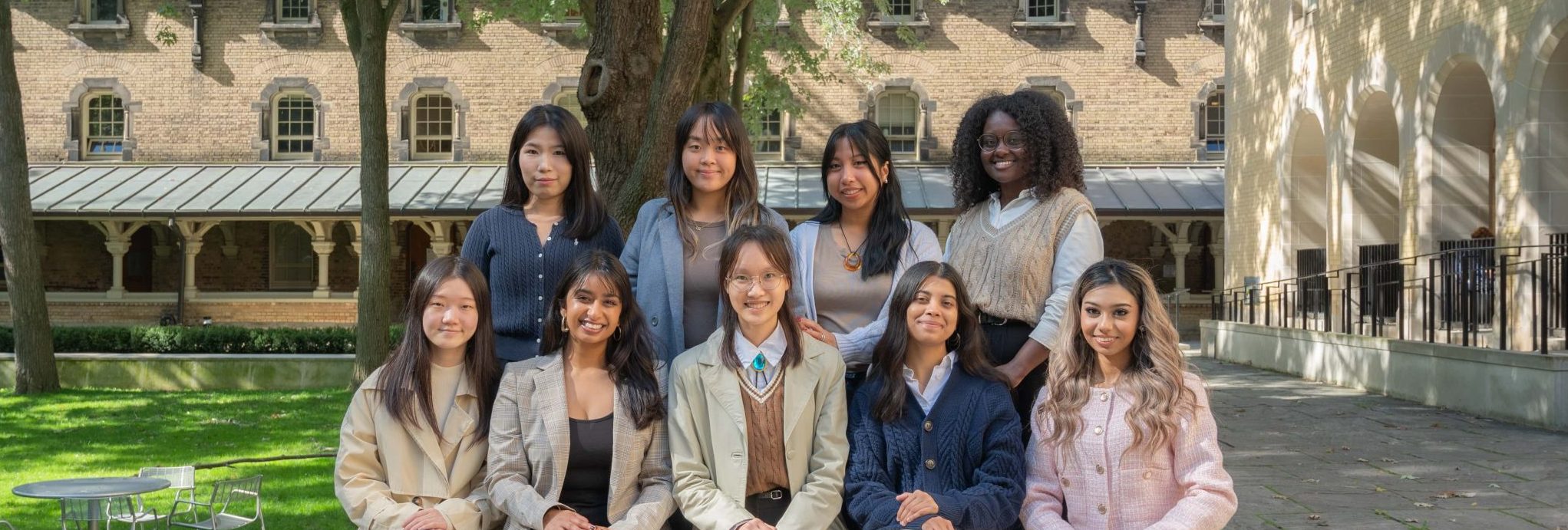 A photo of the Qualitative Data Archives team, featuring nine members standing and sitting outdoors in a courtyard, smiling at the camera.