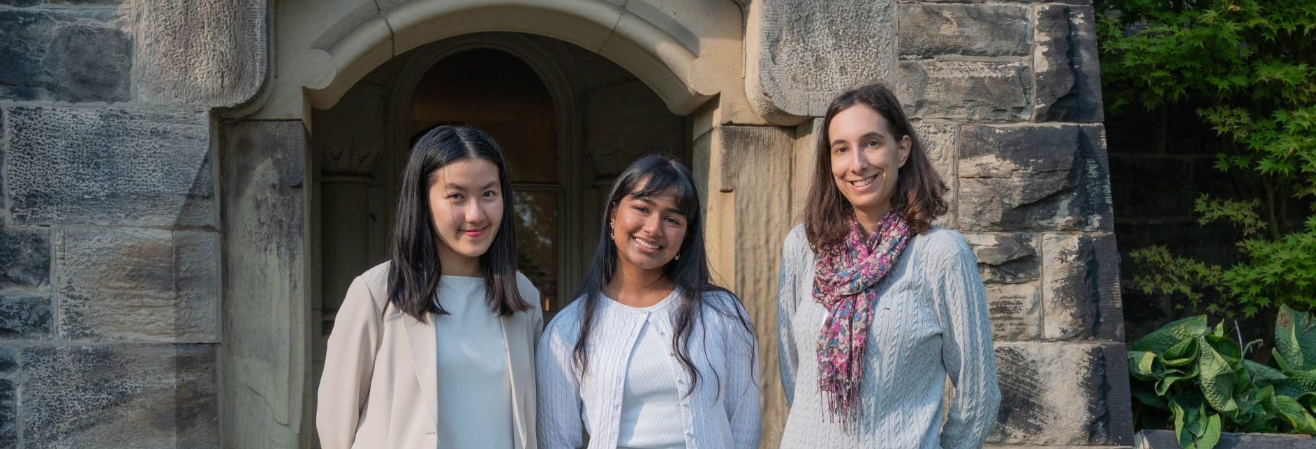 A photo of the community engagement team, featuring three members standing outdoors, smiling at camera.