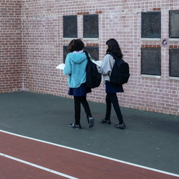 Two high school students walking near a track and school building