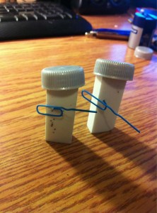 Two erasers standing vertically, with pop bottle caps for helmets and paper clips for rifles