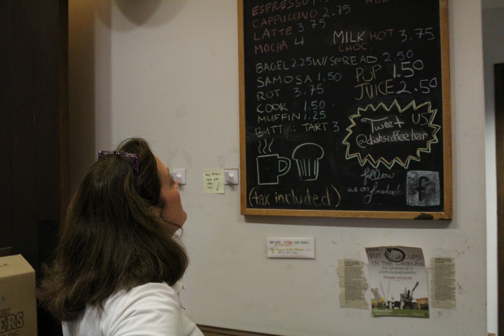 picture of middle aged woman looking up at chalkboard menu of coffee shop