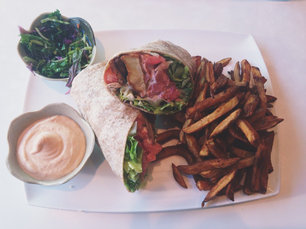 Photo of a whole wheat wrap with tomatoes, lettuce, tofu chicken and fake bacon with a side of fresh cut fries.
