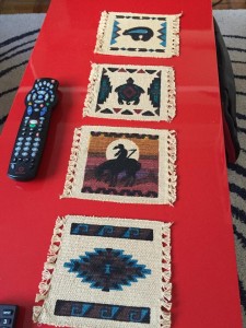 Four coasters, hand-woven beige cloth with rich dark blue, turquoise, and orange  imagery