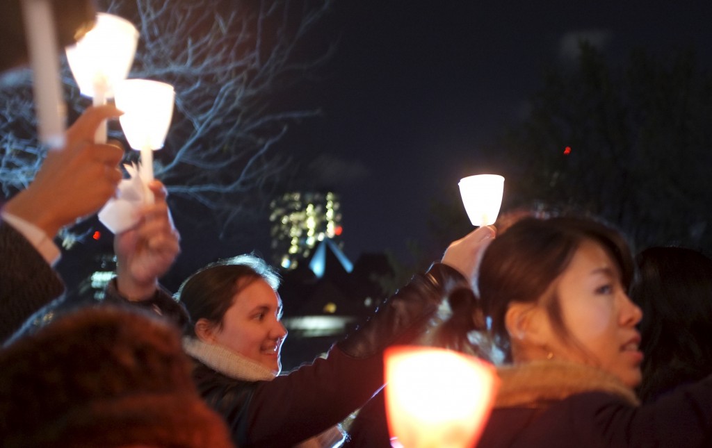 a crowd outside holds up lit candles. 