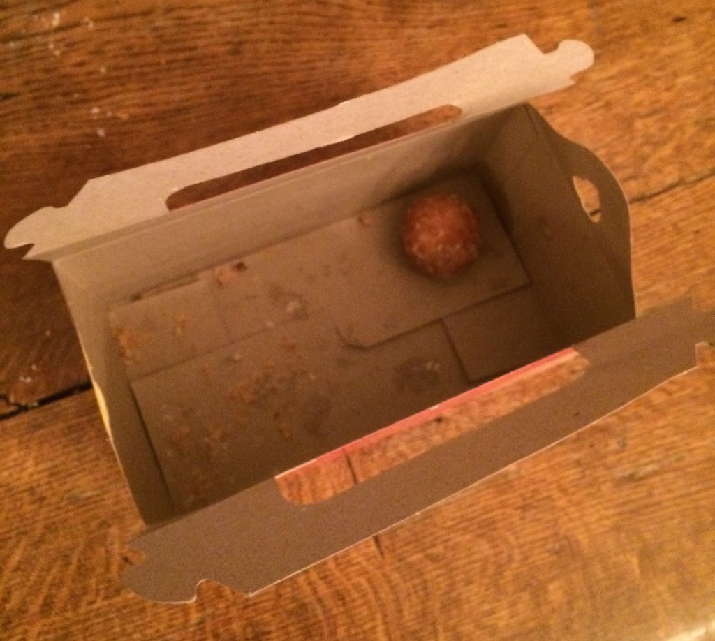 A top view picture of a box of Timbits. There is only one Timbit left!