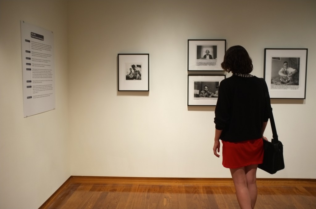 a girl stands facing artwork on a wall, the picture is shot from behind so we see her back and the artwork