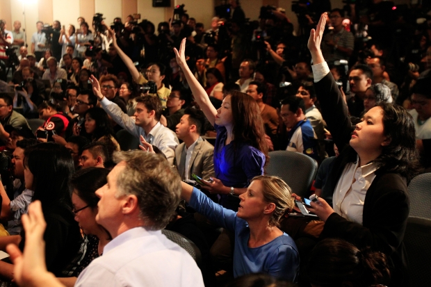 Group of people in a conference hall raising hands to ask questions