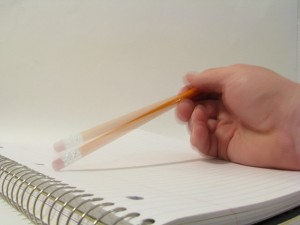 Photo of: a person's hand with a pencil tapping on a notepad