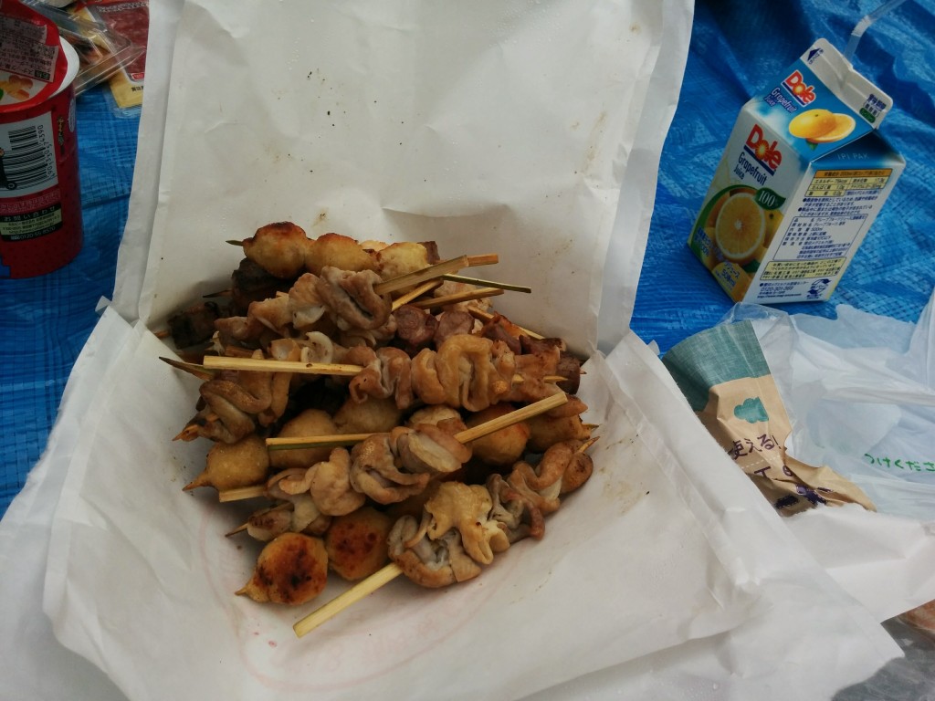 This image shows sticks of yakitori piled on top of a white takeout bag.