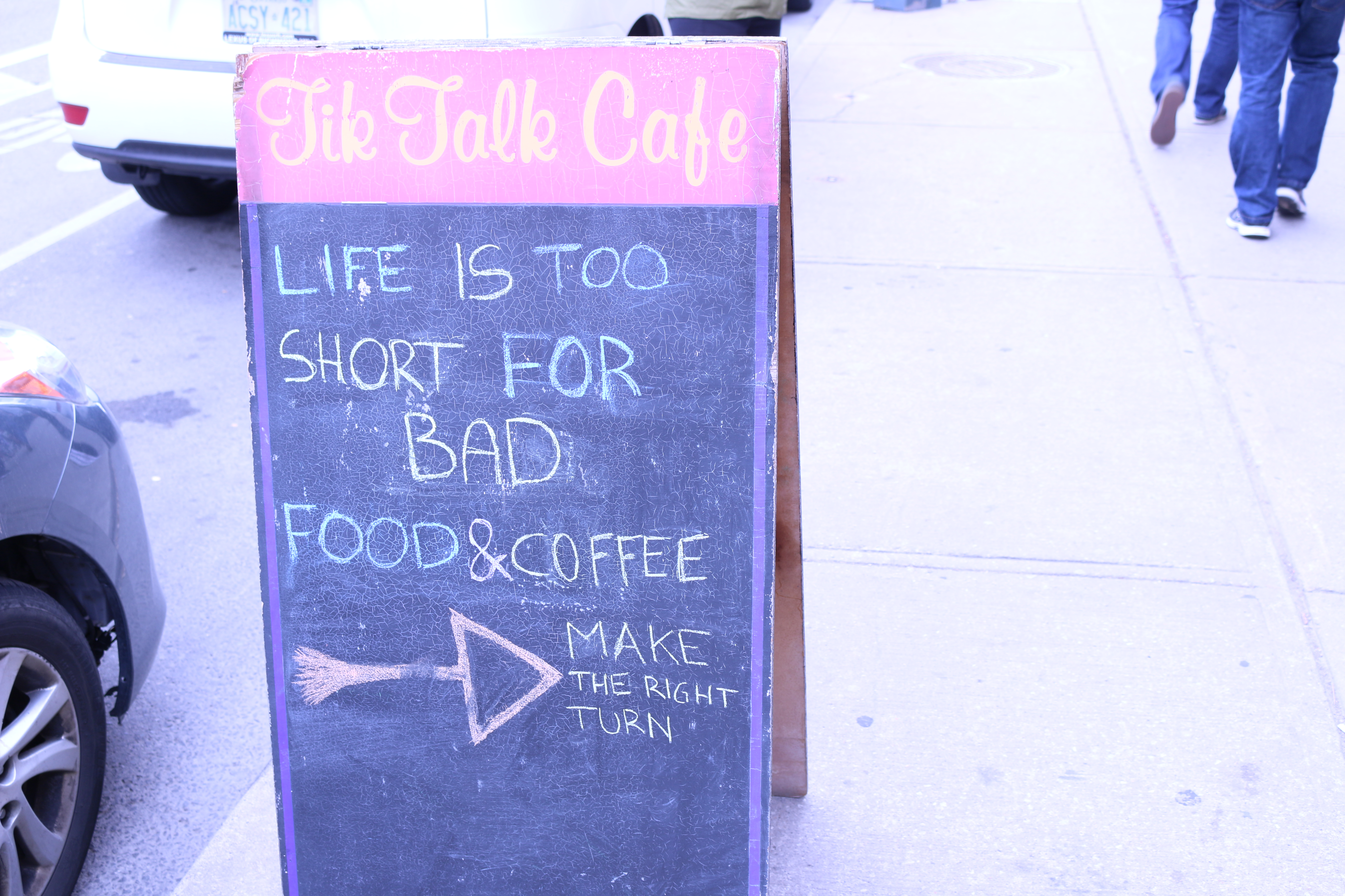 A sign outside Tik Talk Cafe that reads: "Life is too short for bad food and coffee. [arrow to the right pointing inside the cafe] Make the right turn" 