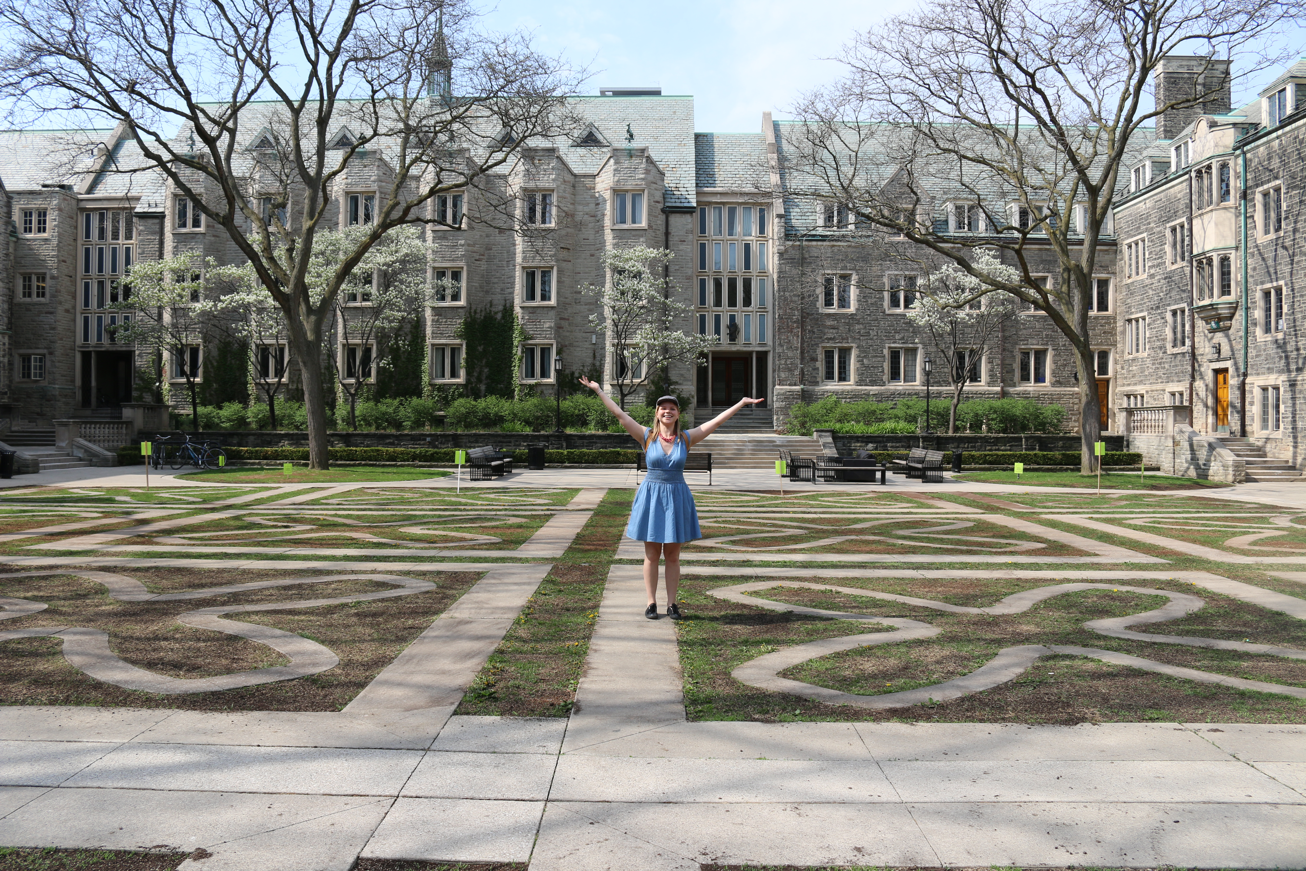 Student Life assistant Laura throws her arms up in the centre of the Trinity College quad.