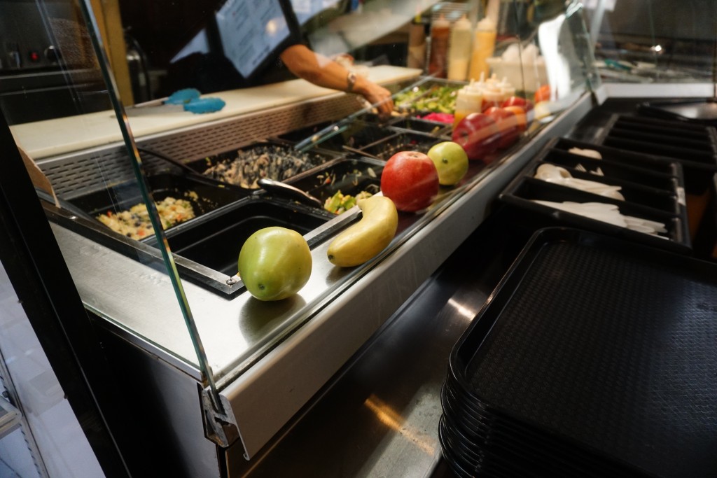 photo of a salad bar with fruits and vegetables in the foreground 