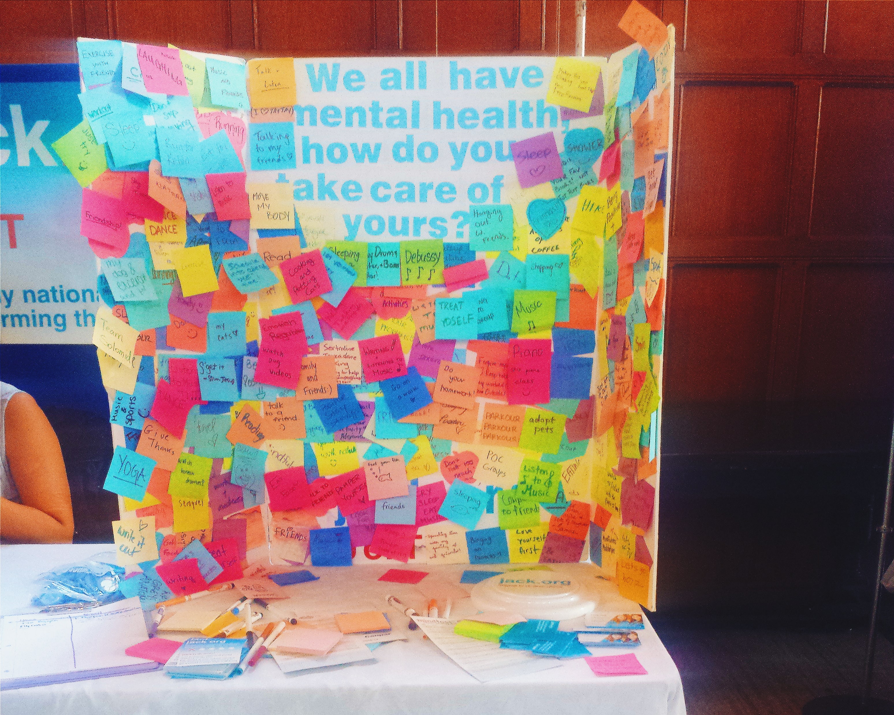 A tri-fold bristol board with the question "We all have mental health. How do you take care of yours?" with sticky note responses all over written by students.