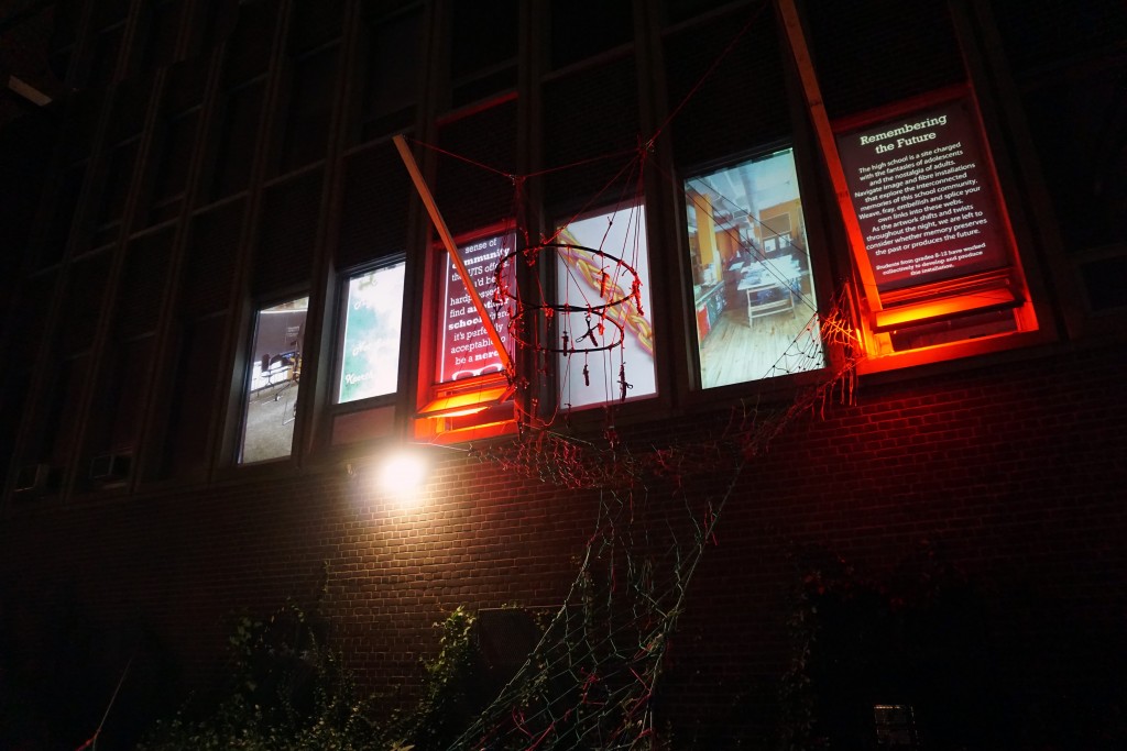 photo of different photos of a school projected on school windows along with a fibre installation in front of the projections 
