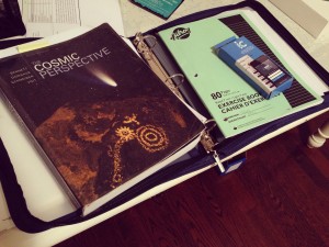 My astronomy textbook and iclicker atop my binder. 