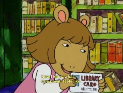 Pictured: DW from PBS's Arthur holding a library card. The caption reads: "Now I know what true power feels like."