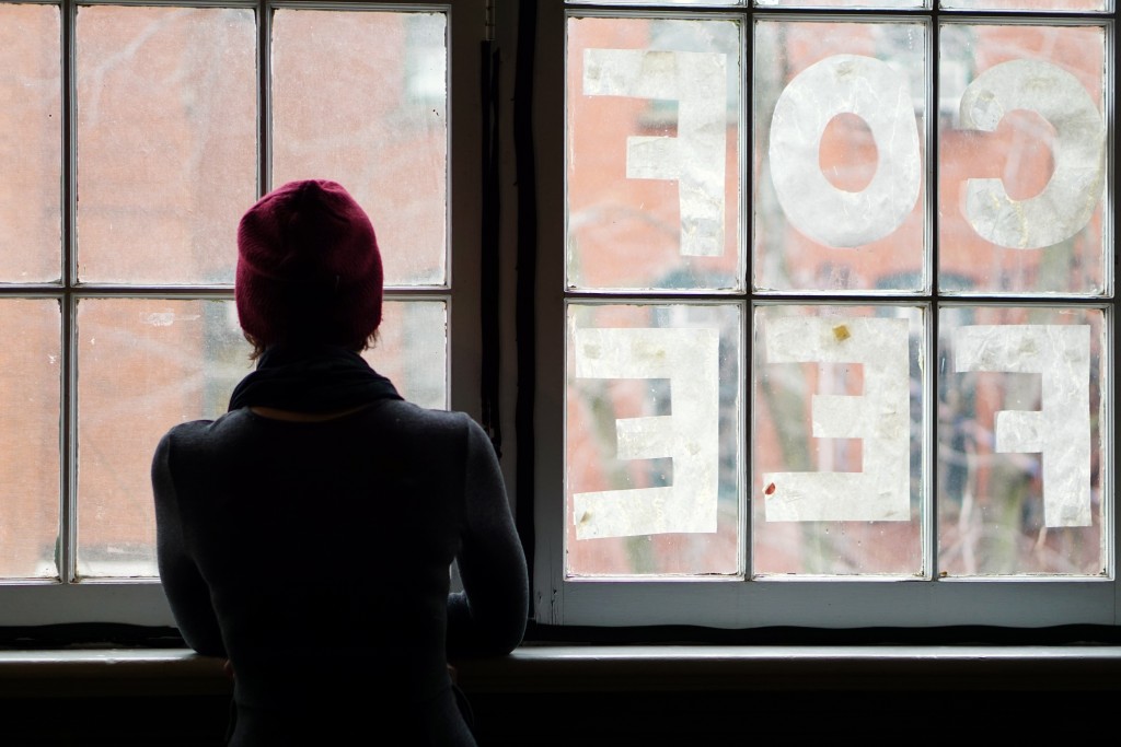 sillohuette of a person looking out the main window of harvest noon, with letters in each window reading "coffee" 