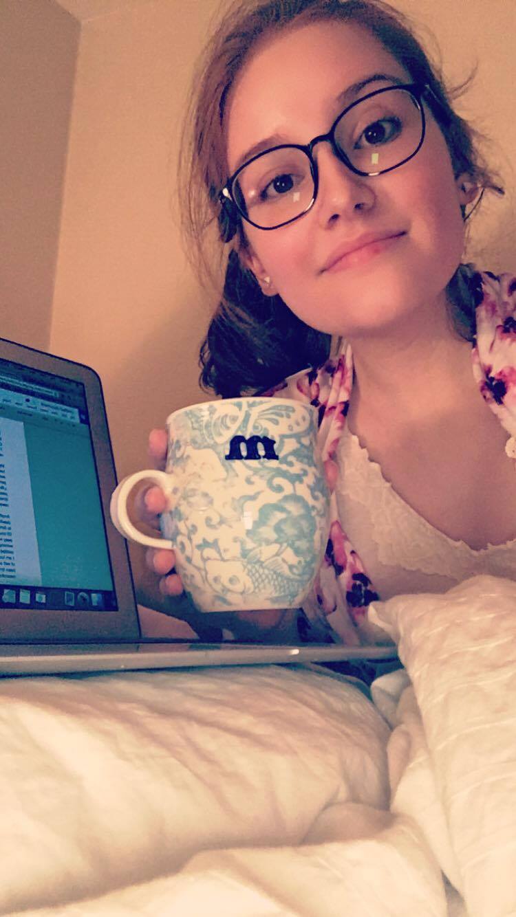 Madeline holding a cup of tea near her laptop, writing her next blog post.