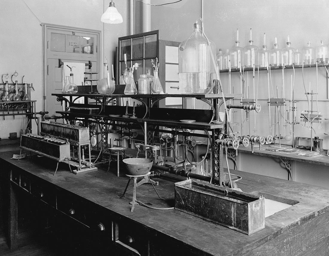 A black and white archival image of the lab where insulin was discovered at U of T showing several glass beakers, tools, and assorted scientific instruments.