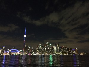 A photograph of the Toronto skyline lit up at night from the ferry on lake ontario