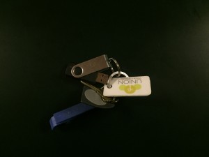 a photo of a set of keys with a blue bottle opener attached to the keychain and a black and steeel usb thumbdrive and a grey fob