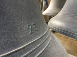 a photo of the large bells of soldier's tower's carillon, the bell in focus has the number 23 etched on it's black surface. There are three bells in the picture