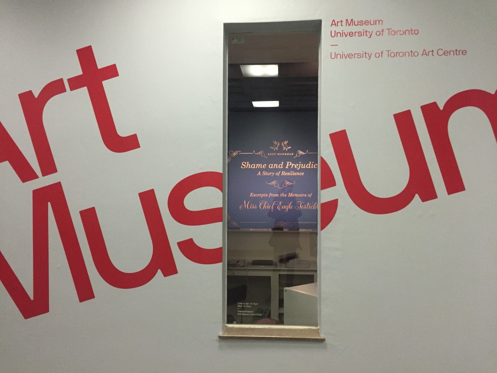 Entrance to the University of Toronto Art Centre (UTAC). The window peers in to the inside where the "Shame and Prejudice" title is displayed on the wall.