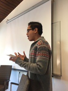 a photo of blogger jasper wearing a grey cardigan against a white screen public speaking