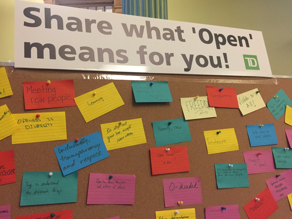 "Share what 'Open' means for you!" reads the direction at the top of the cork board. Various responses are written below on colorful note cards.
