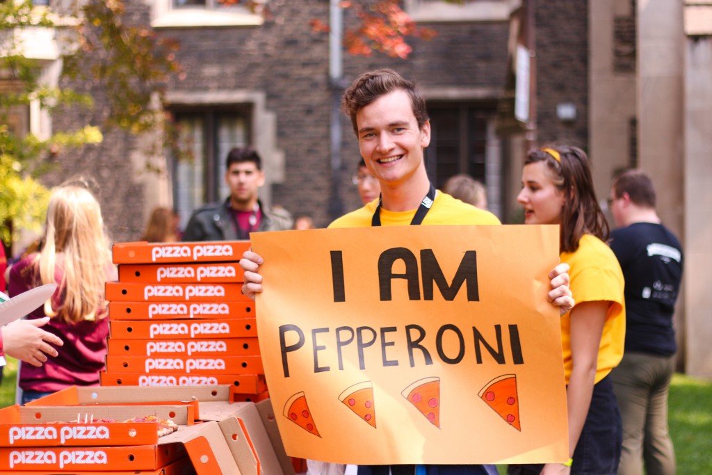 An O-week leader holding a sign saying "I AM PEPPERONI."