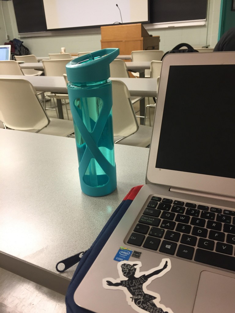 A picture of a water bottle and laptop in a lecture hall.