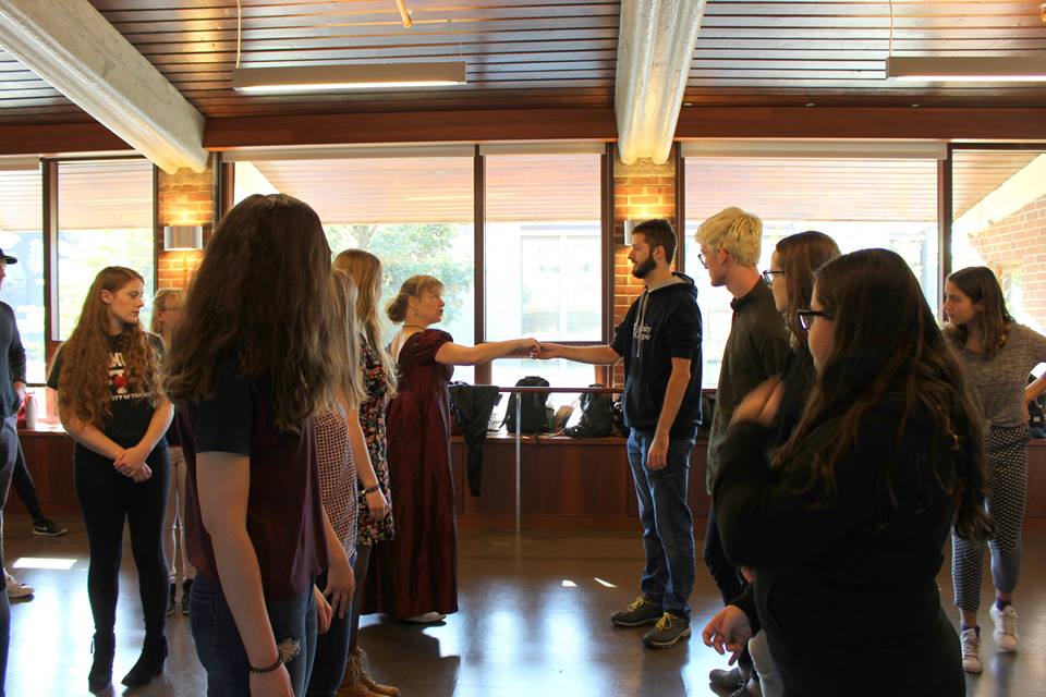 Students stand in a line, learning how to dance.