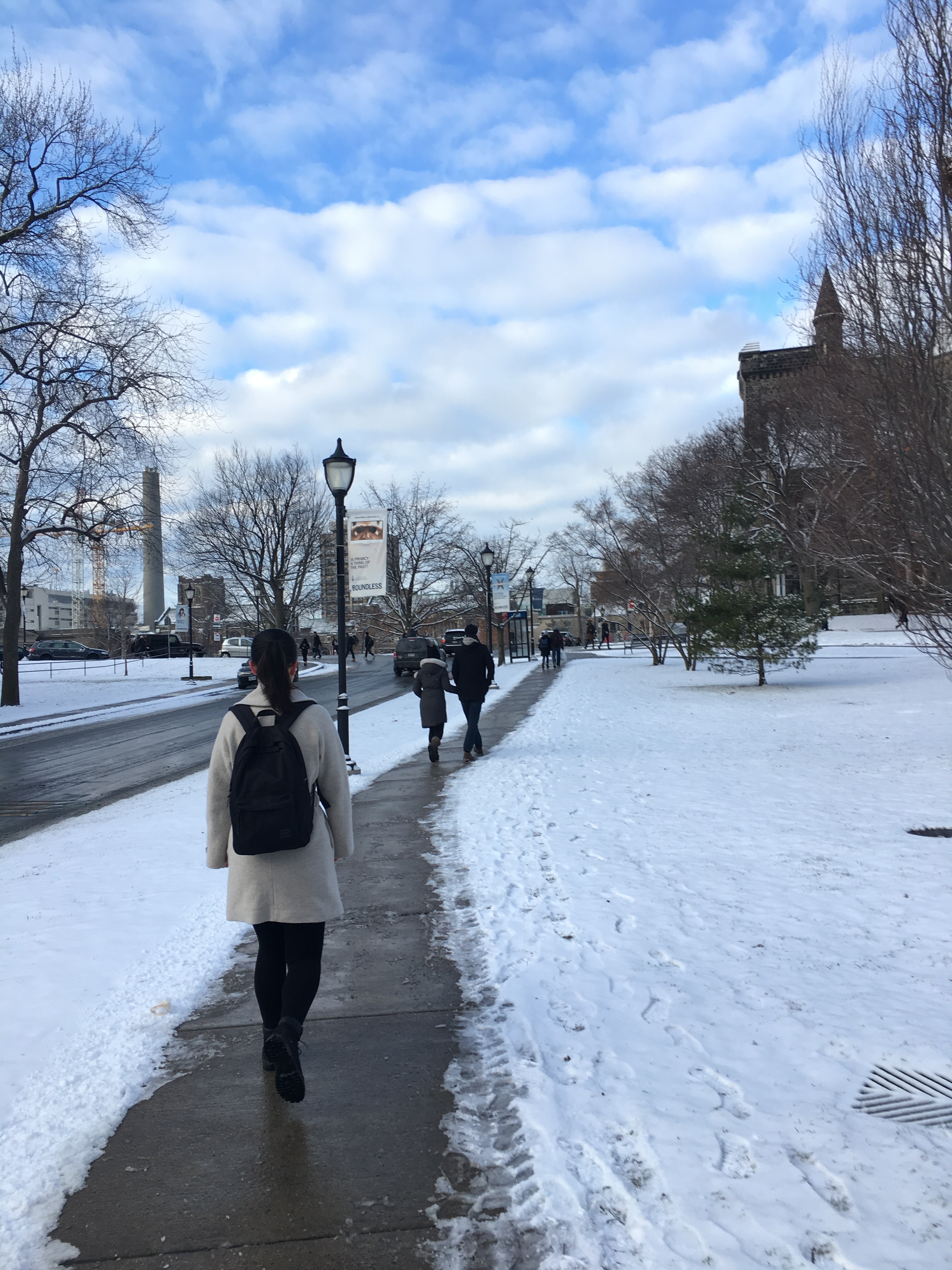 Students walk up a path on a snowy campus.