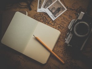 Camera, polaroids and a notebook with a pencil on a map