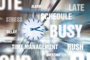 A clock positioned among words like schedule, busy, time management, rush, late, deadline, overtime, alarm, schedule, stress